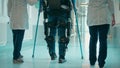 Male patient in the exosuit is walking with the help of doctors