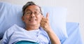 Senior patient smiling and lying down on sickbed in hospital room