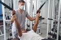 Male patient working out on gym equipment supervised by physiotherapist