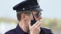 Male patrol officer talking on radio, conveying information regarding criminal