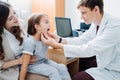 Male pediatrician examining little girl`s tonsils in his office.