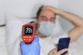 Male person being measured body temperature with a contactless thermometer. A patient in a protective face mask in a