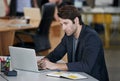 Male person, laptop and working with notebook, stationary and desk in office for startup. Businessman, web and designer Royalty Free Stock Photo