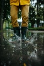 Male person in rubber boots jumping in puddles