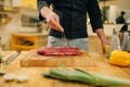 Male person sprinkles raw meat with seasonings