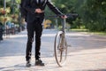 Male person in a suit holding a commuter bike.