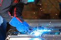 Male person welding metall construction, blue welding arc.