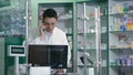 Male pharmacist communicating on phone in pharmacy