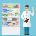 Male pharmacist holding in the hands of the medication in a pharmacy near shelves with medications.