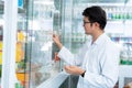 A male pharmacist holding medicine box and capsule pack in pharmacy drugstore Royalty Free Stock Photo