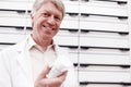 Male pharmacist holding medicine. Portrait of happy mature pharmacist holding medicine near shelf at pharmacy. Royalty Free Stock Photo