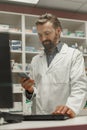 Male pharmacist using the computer and phone while working at the pharmacy Royalty Free Stock Photo