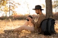 Male photographer in the autumn forest sitting under a tree looking at the results of filming on the screen of a digital Royalty Free Stock Photo