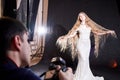 Male photographer taking pictures of model in beautiful shiny dress in photo Studio. Backstage with man and woman during Royalty Free Stock Photo