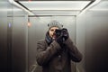 Male photographer taking a self picture in an elevator. Mirror selfie portrait, learning photography and analog film look concept Royalty Free Stock Photo