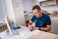 Male physician or nurse writing prescription while sitting on a white desk in a hospital lobby