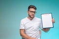 Male physician practitioner in glasses showing blank space sheet for doctor report on blue background. Job in hospital Royalty Free Stock Photo