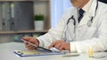 Male physician watching information on tablet, online consultation, healthcare