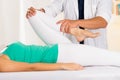 Male physio therapist hands working on female patients legs, holding and bending, blurry clinic background Royalty Free Stock Photo