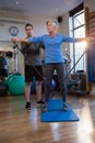 Male physiotherapist helping patient in performing exercise with resistance band