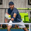 Male pickelball player reaches for the ball during a tournament