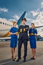Male pilot and air hostesses posing for the camera outdoors Royalty Free Stock Photo