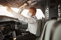 Male pilot turning button on passenger airplane Royalty Free Stock Photo