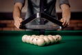 Male player puts white balls with triangle in Russian billiards on green table