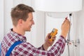 Male Plumber Examining Electric Boiler Royalty Free Stock Photo