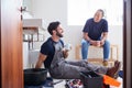 Male Plumber With Female Apprentice Taking A Break From Fixing Leaking Sink In Home Bathroom