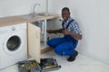 Male Plumber Fixing Sink In Kitchen