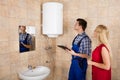 Male Plumber Holding Clipboard Checking Electric Boiler