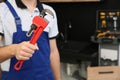 Male plumber holding pipe wrench in kitchen, closeup. Repair service Royalty Free Stock Photo