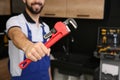 Male plumber holding pipe wrench in kitchen. Repair service Royalty Free Stock Photo