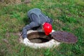 A male plumber opened the hatch of a water well and looks inside. Inspection of water pipes and meters Royalty Free Stock Photo