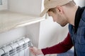 Male plumber repairing radiator with wrench.