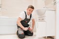 A male plumber repairs siphon under the sink in the bathroom.