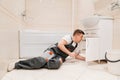 A male plumber repairs siphon under the sink in the bathroom.