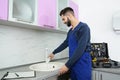 Male plumber in uniform checking faucet. Repair service Royalty Free Stock Photo