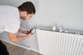 Man installing heating radiator in apartment under renovation.