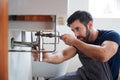 Male Plumber Using Wrench To Fix Leaking Sink In Home Bathroom Royalty Free Stock Photo