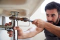 Male Plumber Using Wrench To Fix Leaking Sink In Home Bathroom Royalty Free Stock Photo