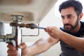 Male Plumber Using Wrench To Fix Leaking Sink In Home Bathroom Royalty Free Stock Photo