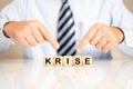 Male pointing to wooden cubes with the letters making the German word Krise meaning crisis Royalty Free Stock Photo