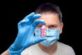 Male portrait a doctor in a medical mask holds in hand on sterile glove a glass bottle. Royalty Free Stock Photo