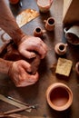 Male potter molding a clay in pottery workshop, close-up, selective focus, top view.