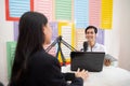 a male presenter chats with a woman using a microphone during a podcast