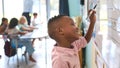 Male Primary Or Elementary School Student Writing On Whiteboard In Classroom Lesson Royalty Free Stock Photo