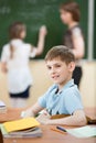 Male primary school student in classroom with classmate and teacher Royalty Free Stock Photo