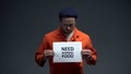 Male prisoner holding Need normal food sign, ill treatment in jail, starving